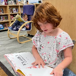 An HPES student sits on a bench in the library reading a book.